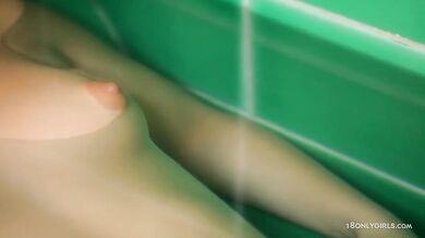 Teen plays in the bathtub with shower head