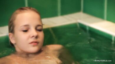 Teen plays in the bathtub with shower head